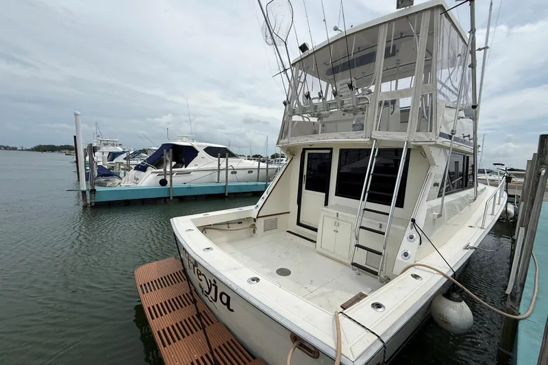 Slide: The Image of 1989 Viking 41 Convertible yacht docked at marina, featuring spacious deck and fishing equipment. - 4