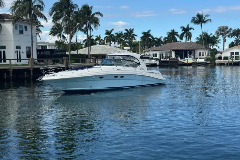 Slide: The Image of 2005 Sea Ray 420 Sundancer yacht on calm water, surrounded by palm trees and waterfront homes. - 1