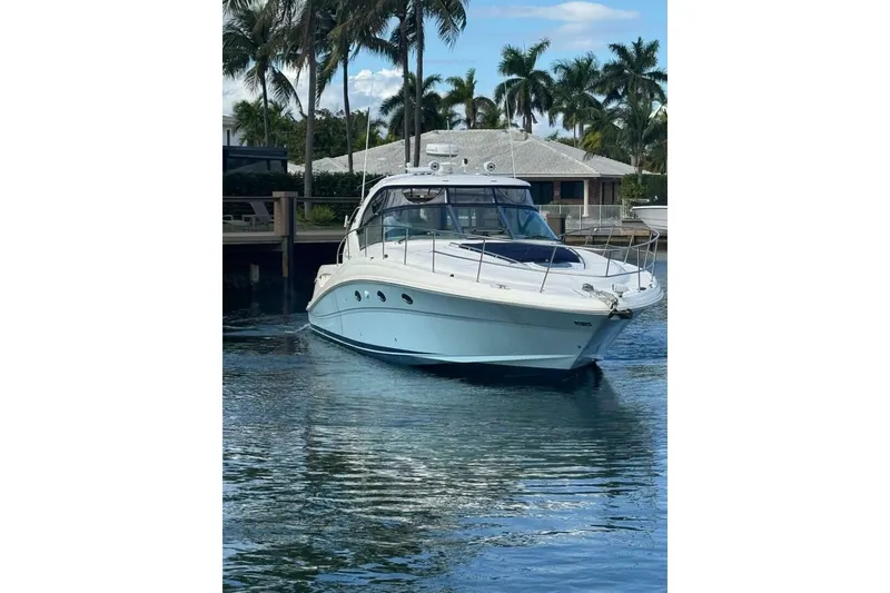Slide: The Image of 2005 Sea Ray 420 Sundancer yacht docked near palm trees and waterfront home. - 2