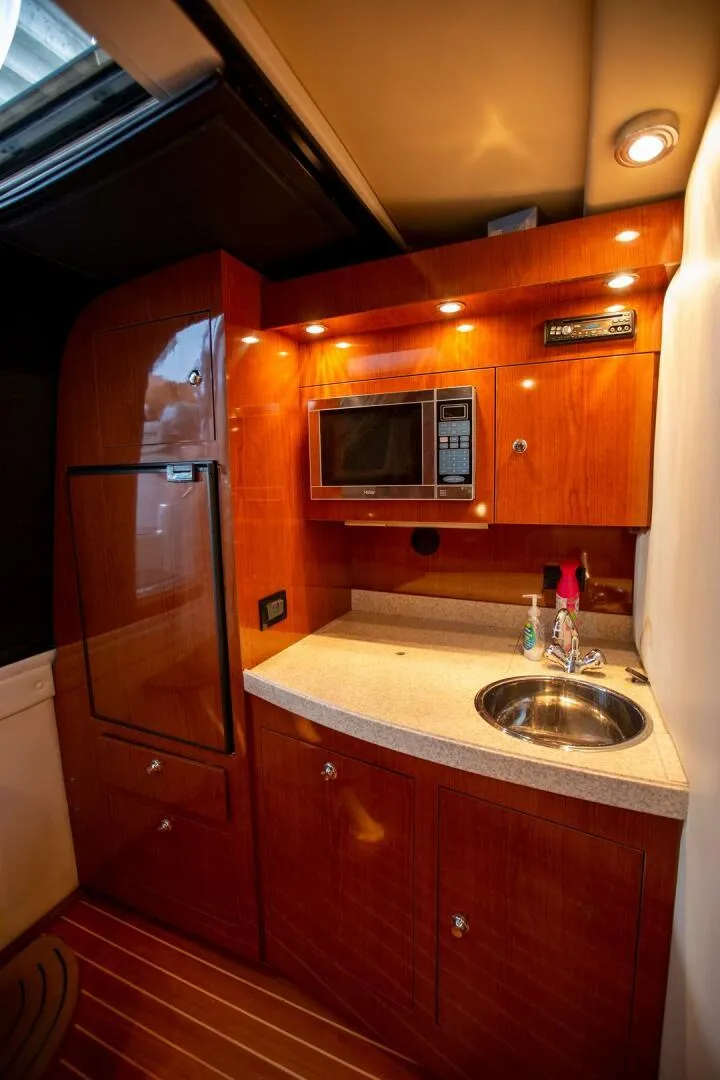 Slide: The Image of 2008 Regal 38 yacht kitchen with wood cabinetry, microwave, sink, and ambient lighting. - 8