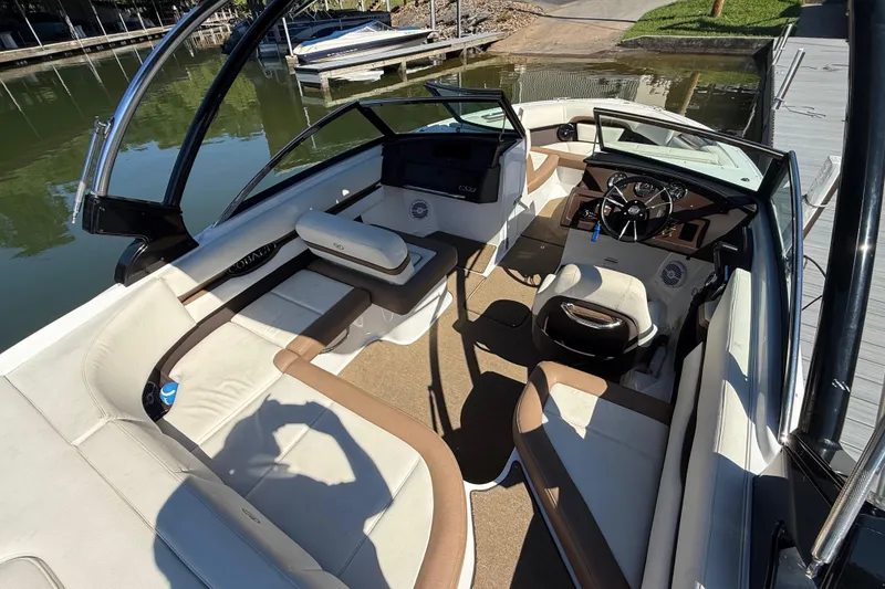 Slide: The Image of 2018 Cobalt CS22 boat interior with beige seating and sleek dashboard, docked by the water. - 11