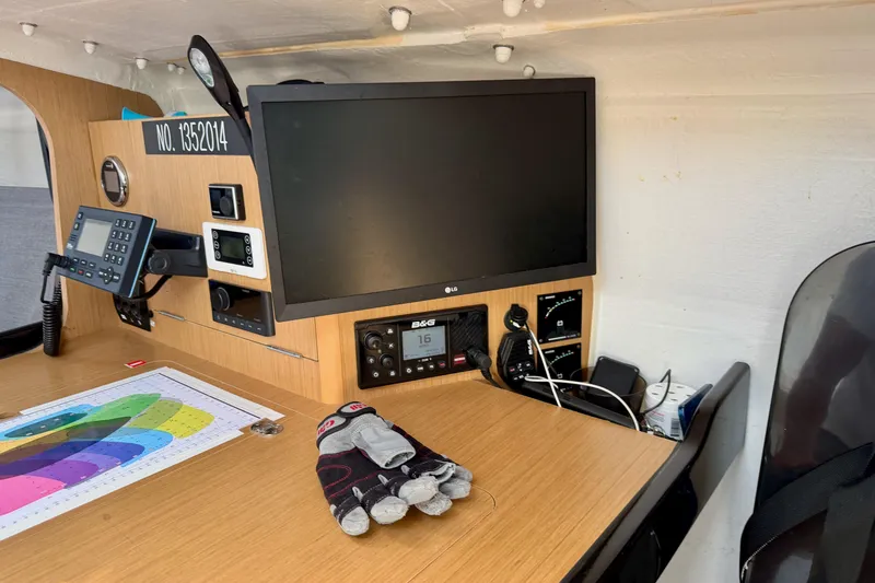 Slide: The Image of Navigation station inside 2020 Jeanneau Sun Fast 3300 yacht with electronic equipment and sailing gloves. - 49