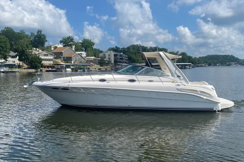 The Image of 2001 Sea Ray 340 Sundancer boat on a calm lake with houses in the background. - 0