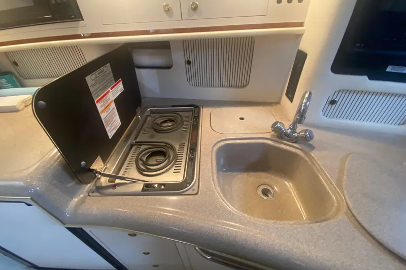 Slide: The Image of 2001 Sea Ray 340 Sundancer kitchen with stove and sink in compact layout. - 19