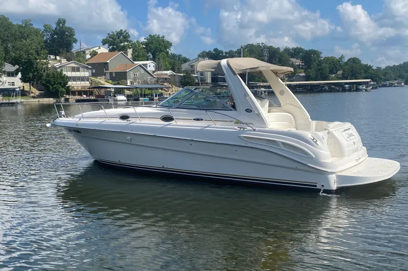 Slide: The Image of 2001 Sea Ray 340 Sundancer yacht on a serene lake with houses in the background. - 1