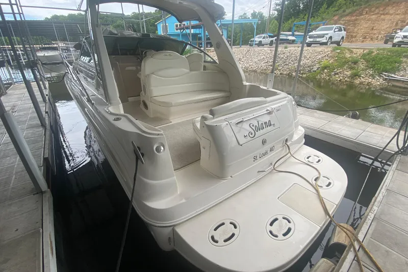 Slide: The Image of 2001 Sea Ray 340 Sundancer docked, rear view showing seating and boat name "Solano". - 3