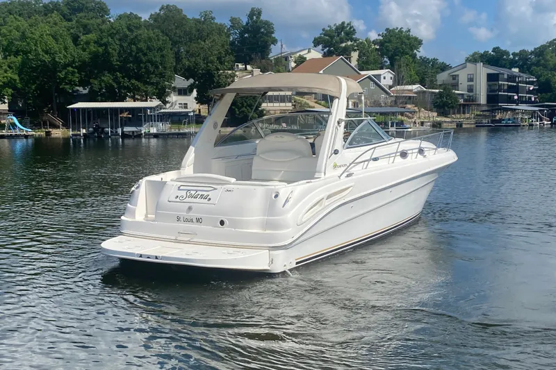 Slide: The Image of 2001 Sea Ray 340 Sundancer boat on a calm lake with houses in the background. - 4