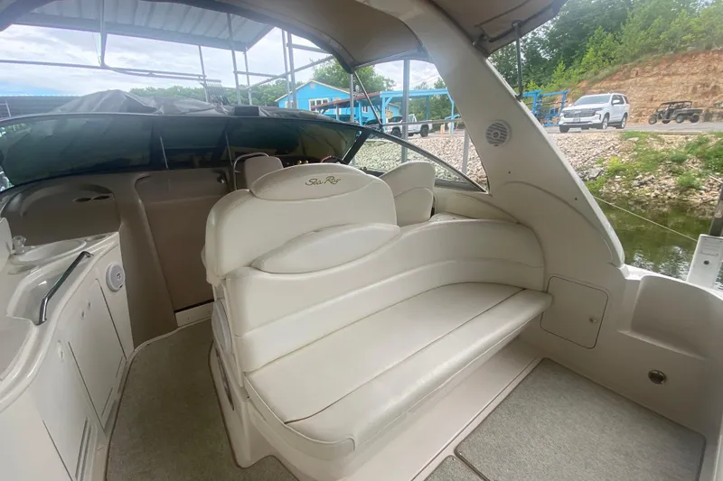 Slide: The Image of 2001 Sea Ray 340 Sundancer interior with white seating and helm, docked by the water. - 6