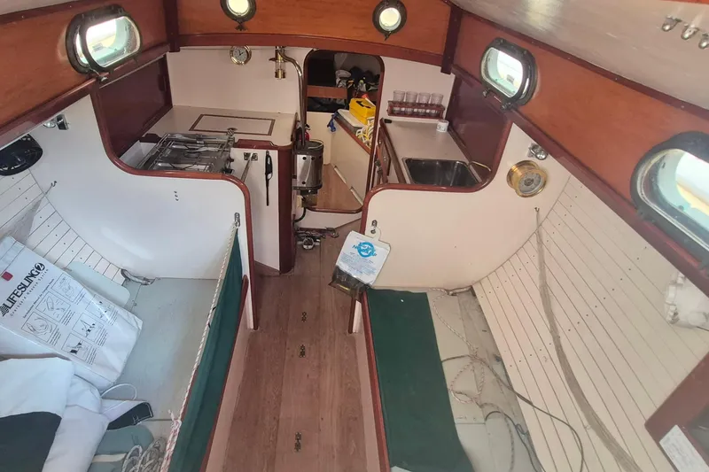 Slide: The Image of Interior of a 1996 Morris Yachts Frances sailboat, featuring a compact kitchen and cozy cabin space. - 10