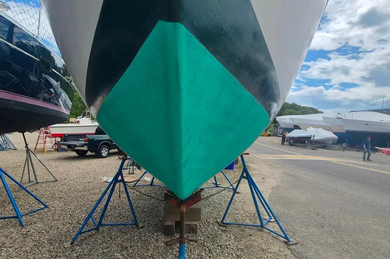 Slide: The Image of 1996 Morris Yachts Frances sailboat on stands, with turquoise hull, in a boatyard. - 49