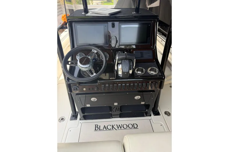 Slide: The Image of Control panel of a 2015 Blackwood 27 boat with steering wheel and displays. - 12