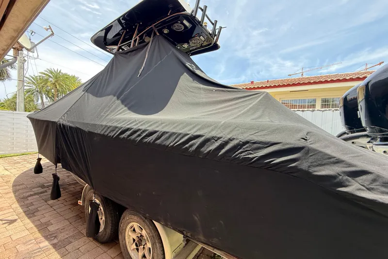 Slide: The Image of Covered 2015 Blackwood 27 boat on trailer, parked outdoors under clear sky. - 2