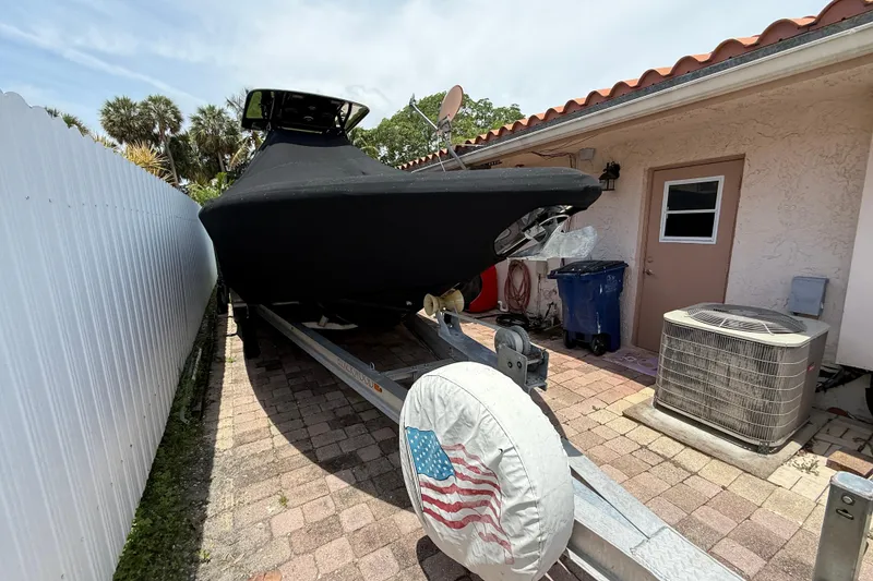 Slide: The Image of Covered Blackwood 27 boat on trailer beside house, American flag tire cover, 2015 model. - 27