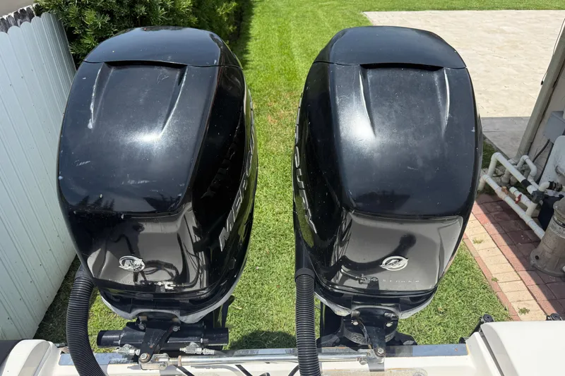 Slide: The Image of Twin Mercury outboard engines on a 2015 Blackwood 27 boat, parked on grass. - 9