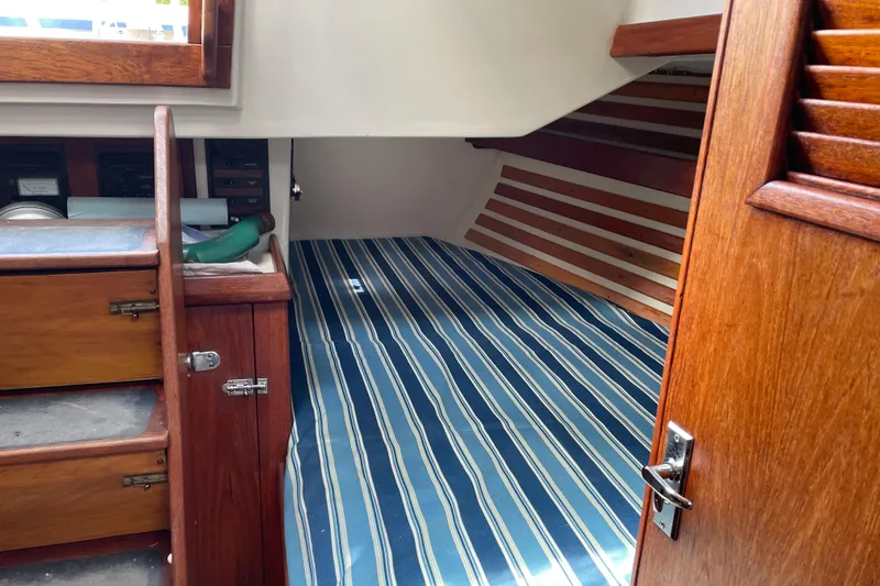 Slide: The Image of Interior cabin of 1981 Hinterhoeller Niagara 35 sailboat with striped bedding and wooden cabinetry. - 10