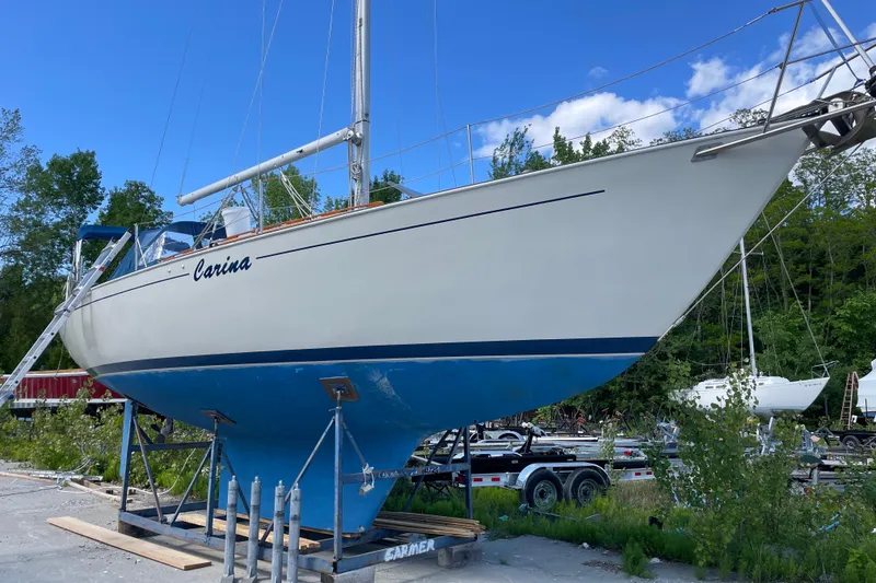 Slide: The Image of 1981 Hinterhoeller Niagara 35 sailboat on land, blue hull, clear sky background. - 13