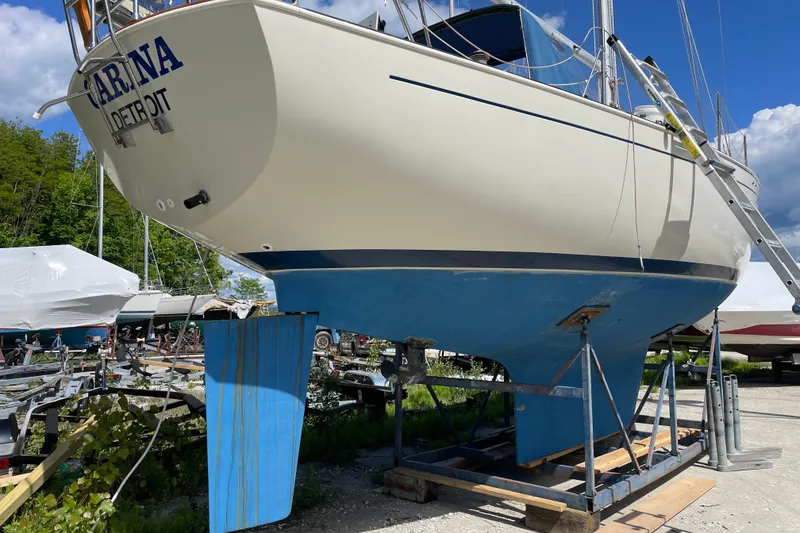 Slide: The Image of 1981 Hinterhoeller Niagara 35 sailboat on dry dock, blue hull, clear sky background. - 14