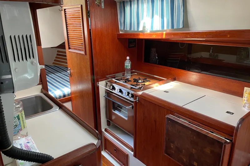 Slide: The Image of Interior of 1981 Hinterhoeller Niagara 35 sailboat, featuring a compact kitchen with wood cabinetry. - 8