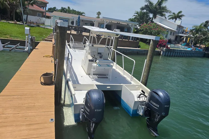 Slide: The Image of 2014 Custom Exuma Catamaran 32 docked, featuring twin Yamaha 150 engines, in a scenic waterfront setting. - 6