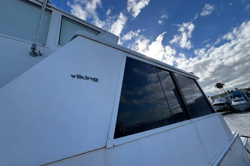Slide: The Image of 1999 Viking 60 CPMY yacht with sleek design under a partly cloudy sky. - 11