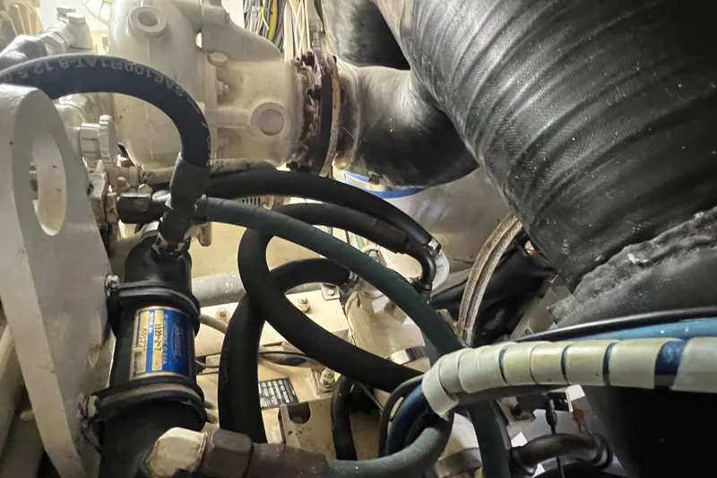 Slide: The Image of Engine compartment of a 1999 Viking 60 CPMY yacht, featuring hoses and mechanical components. - 133