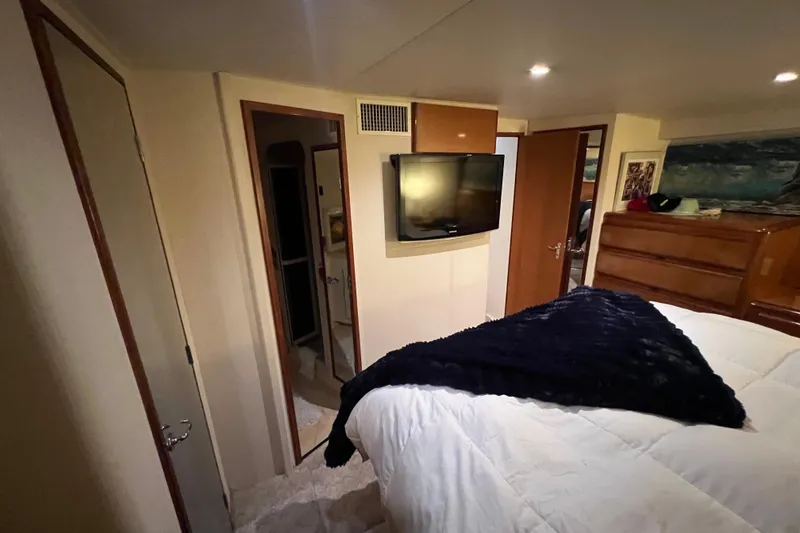 Slide: The Image of 1999 Viking 60 CPMY yacht bedroom with TV, dresser, and cozy bedding. - 99