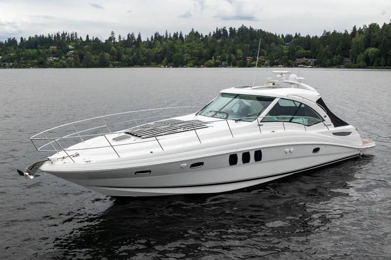 The Image of 2010 Sea Ray 500 Sundancer yacht cruising on a serene lake with forested shoreline. - 0
