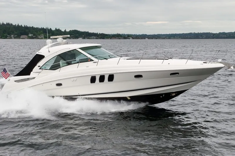 Slide: The Image of 2010 Sea Ray 500 Sundancer yacht cruising on a lake with American flag. - 1
