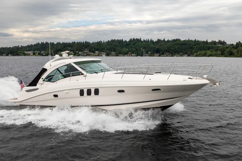 Slide: The Image of 2010 Sea Ray 500 Sundancer yacht cruising on a lake with forested shoreline. - 32