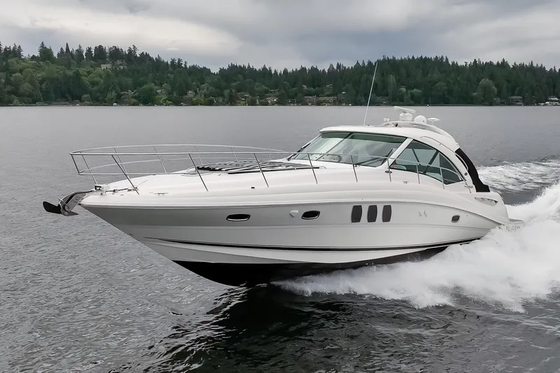 Slide: The Image of 2010 Sea Ray 500 Sundancer cruising on a serene lake with lush forest backdrop. - 5