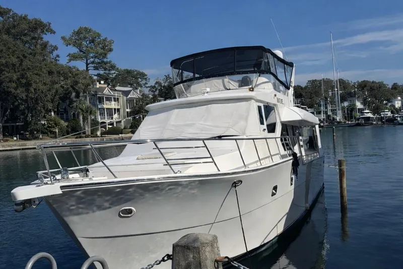 Slide: The Image of 2003 Altima 55 Pilothouse yacht docked in a serene marina setting. - 1