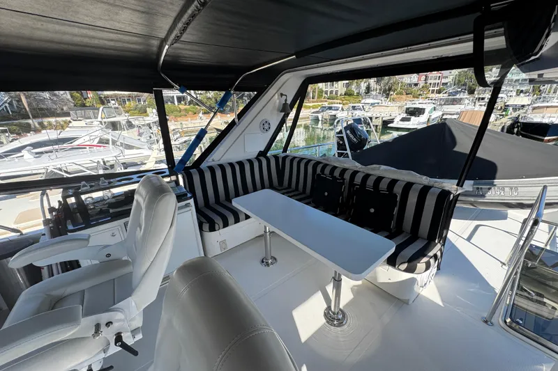 Slide: The Image of 2003 Altima 55 Pilothouse interior with striped seating and marina view. - 17
