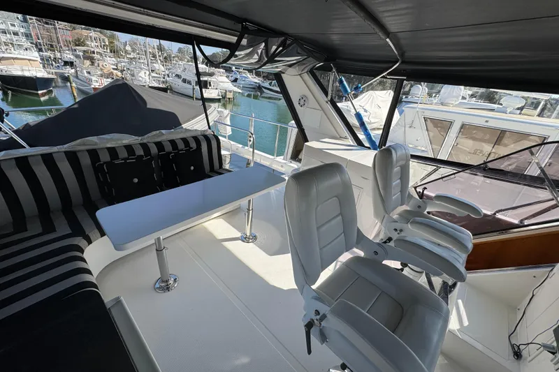 Slide: The Image of 2003 Altima 55 Pilothouse yacht interior with seating and table, docked at marina. - 18