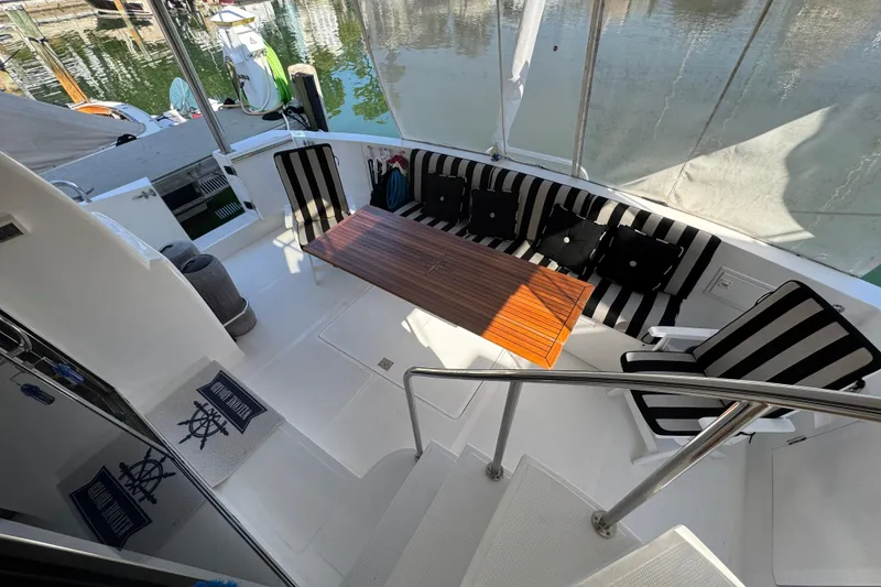 Slide: The Image of 2003 Altima 55 Pilothouse yacht deck with striped seating and wooden table. - 21