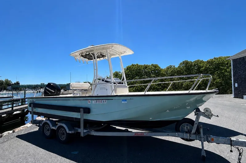 The Image of 2021 Boston Whaler 210 Montauk boat on trailer, parked near marina under clear blue sky. - 0
