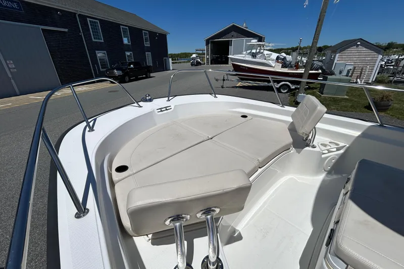 Slide: The Image of 2021 Boston Whaler 210 Montauk boat interior with cushioned seating, docked at a marina. - 16