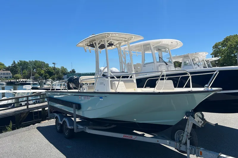 Slide: The Image of 2021 Boston Whaler 210 Montauk boat on trailer at marina under clear blue sky. - 2