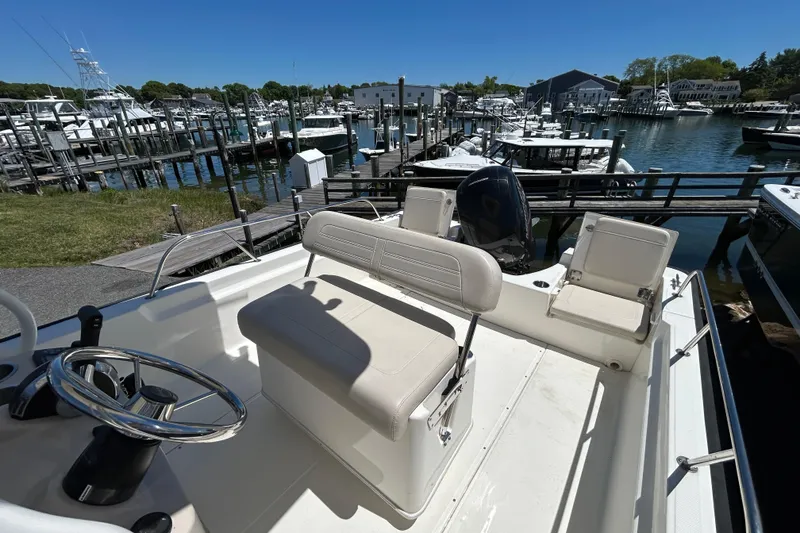 Slide: The Image of 2021 Boston Whaler 210 Montauk boat docked at a marina under clear blue skies. - 5