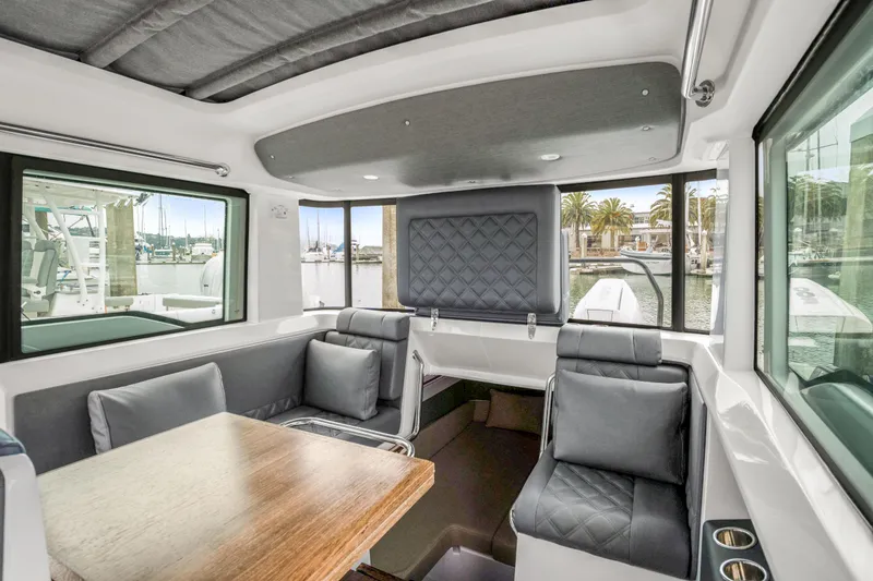 Slide: The Image of Interior of 2021 Axopar 37 XC Cross Cabin with seating and table, marina view. - 20
