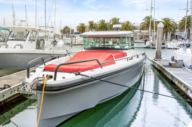 Slide: The Image of 2021 Axopar 37 XC Cross Cabin docked in a marina with red seating. - 44