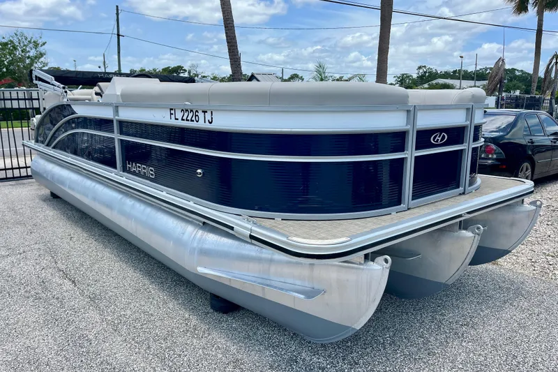The Image of 2023 Harris Cruiser 230 pontoon boat parked on gravel lot under blue sky. - 1