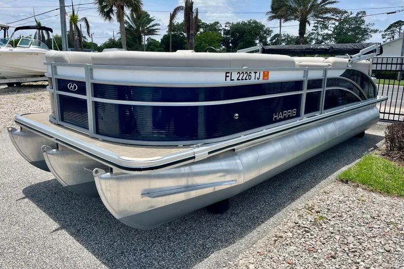 Slide: The Image of 2023 Harris Cruiser 230 pontoon boat parked on a sunny day. - 2
