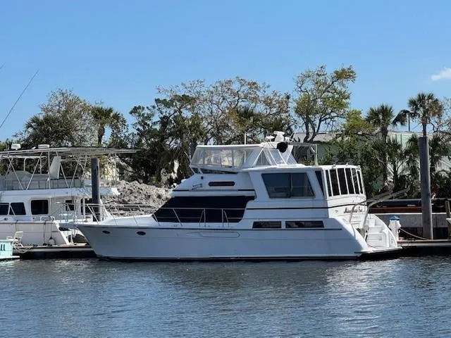 The Image of 1998 Hyatt 51 Aft Cabin Motor Yacht docked in a marina, surrounded by trees. - 0