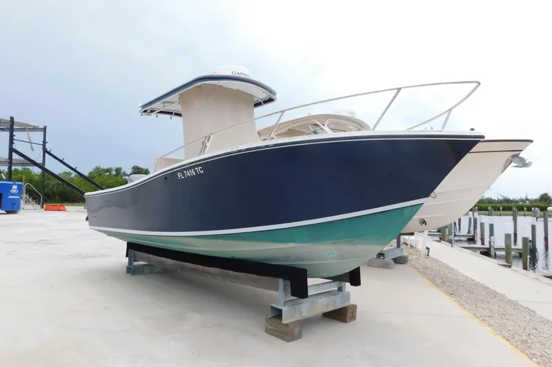Slide: The Image of 1996 Regulator 23 Center Console boat on a dock, featuring a sleek blue and white design. - 2