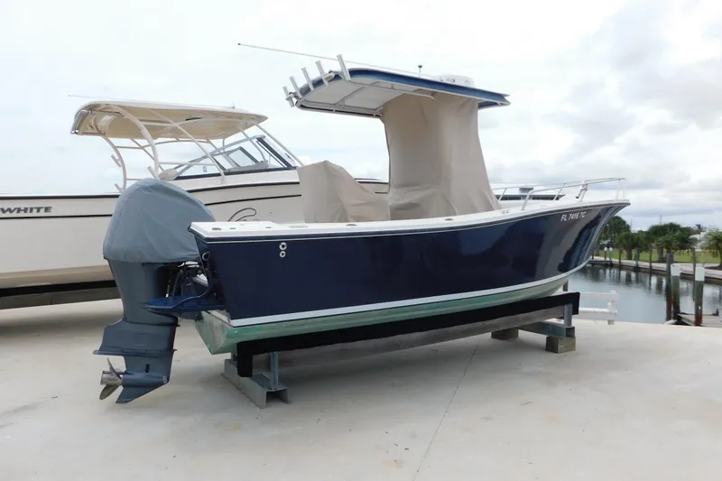 Slide: The Image of 1996 Regulator 23 Center Console boat on a stand, covered, near a marina. - 4