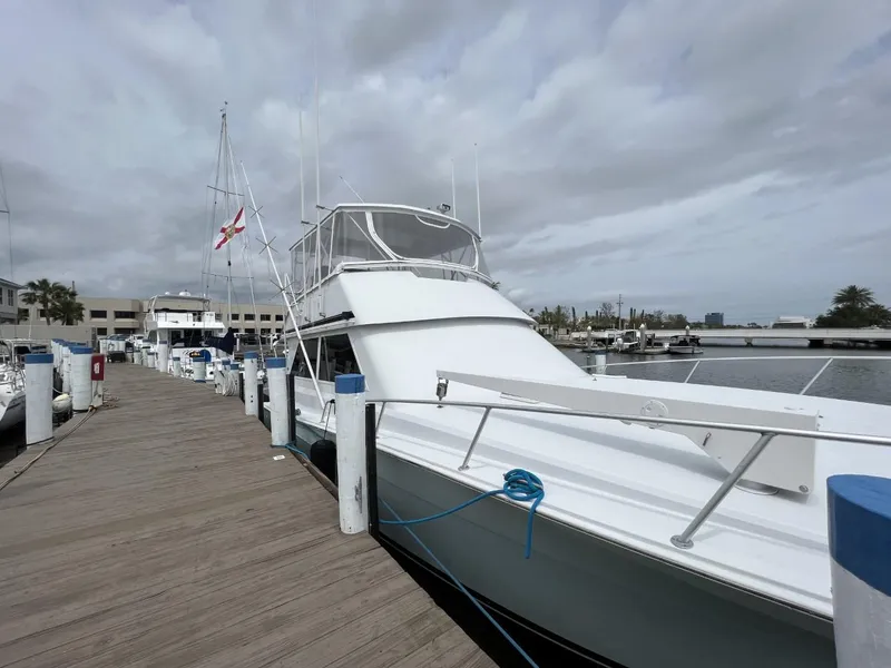 Slide: The Image of 1991 Viking Convertible yacht docked at a marina under cloudy skies. - 1
