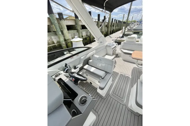 Slide: The Image of 2023 Sea Ray 290 Amberjack boat interior with helm, seating, and dock view. - 10
