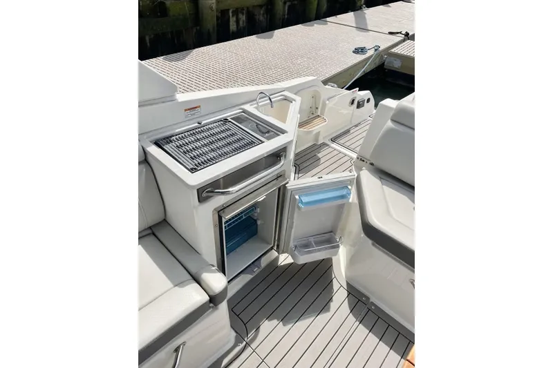 Slide: The Image of 2023 Sea Ray 290 Amberjack boat interior with open mini fridge and grill. - 13