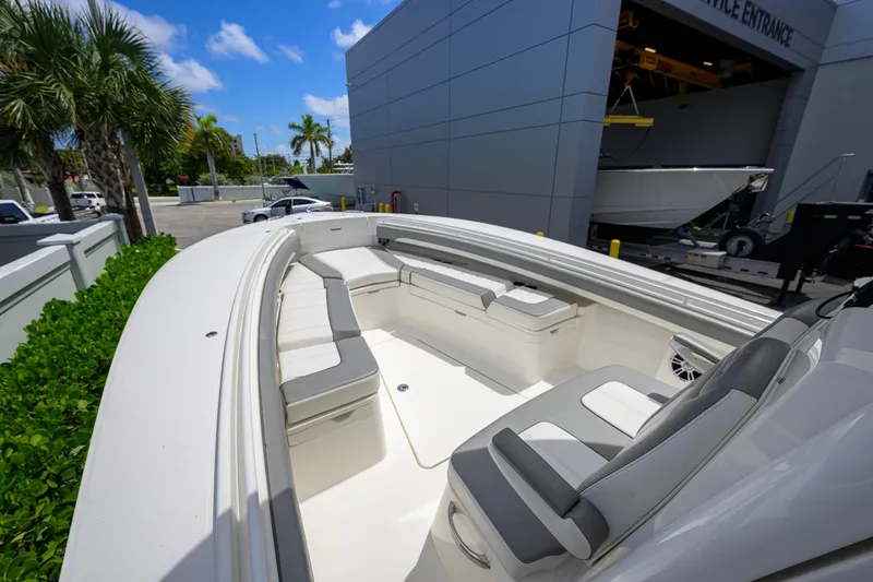 Slide: The Image of 2023 Regulator 28 boat with spacious seating, docked near palm trees and a modern building. - 12