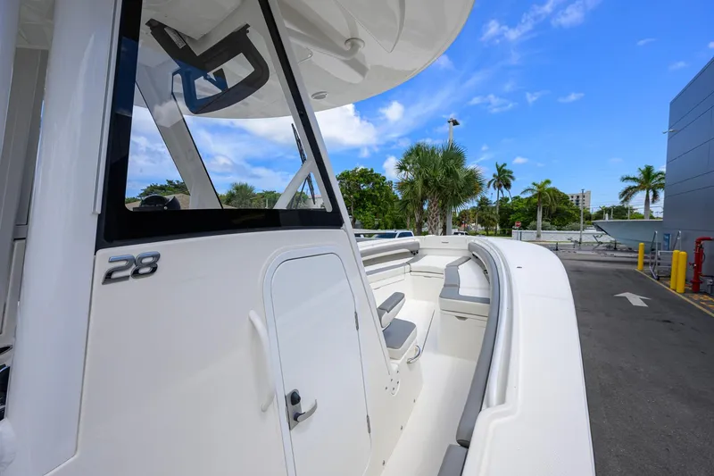 Slide: The Image of 2023 Regulator 28 boat with sleek design, docked under clear blue sky. - 23